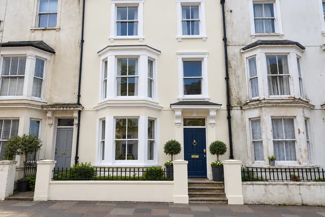 The same terrace freshly painted cream with crisp white windows and a navy front door.